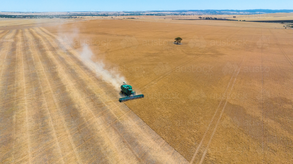 Dry-land farming machinery harvesting crop in farm paddock - Australian Stock Image