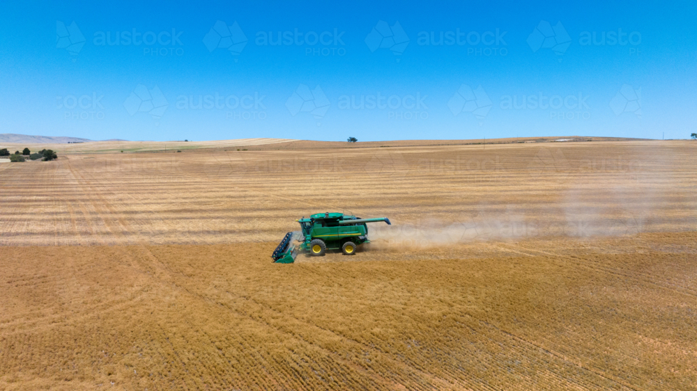 Dry-land farming machinery harvesting crop in farm paddock - Australian Stock Image