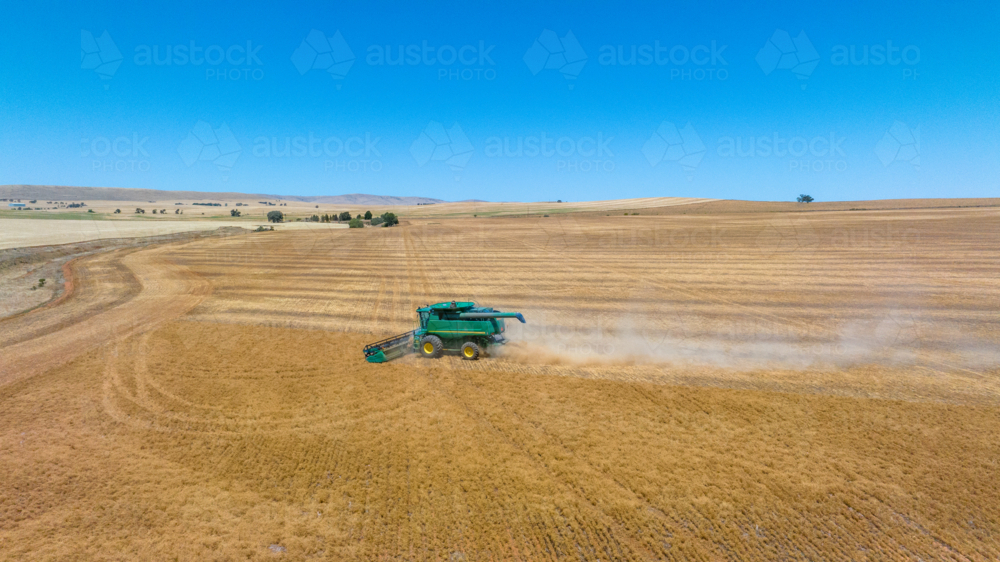 Dry-land farming machinery harvesting crop in farm paddock - Australian Stock Image