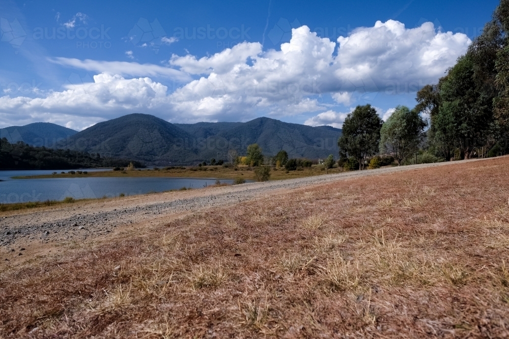 Dry valley bed with lush mountains on the background - Australian Stock Image