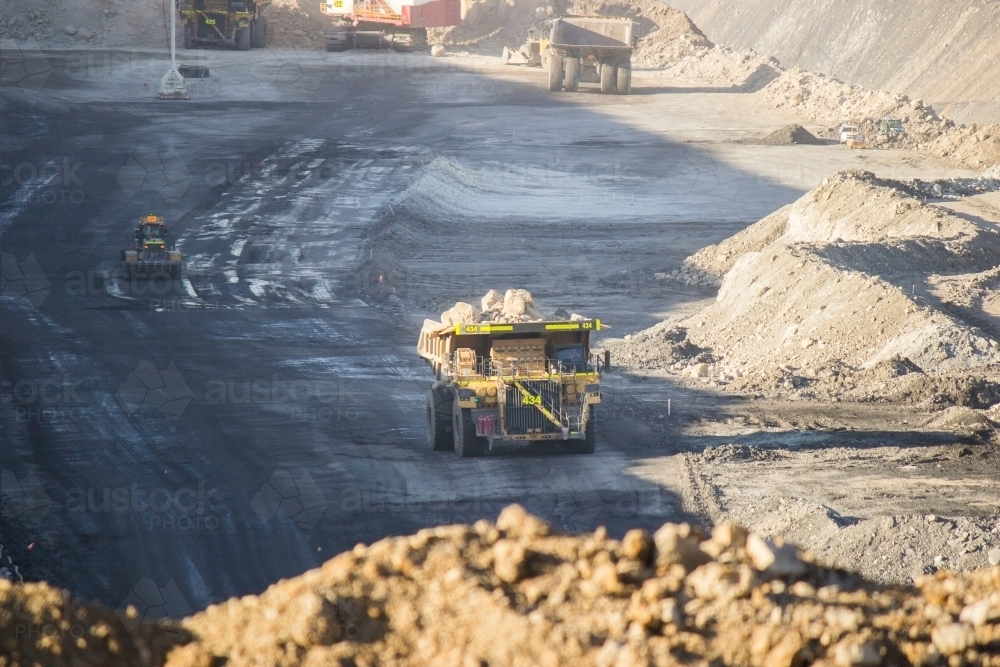 Dump trucks filling up with overburden and carting it through open cut coal mine - Australian Stock Image