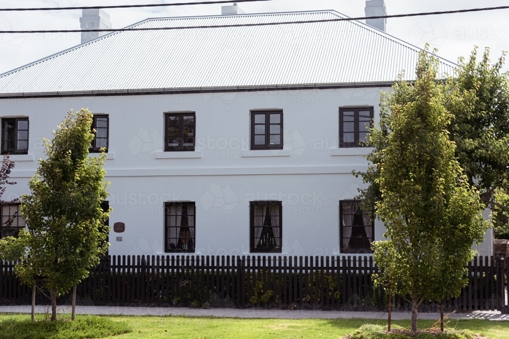 Early Georgian  white two storey country home with a black  Pickett fence - Australian Stock Image