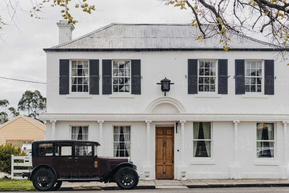 Early historic white Georgian style house with black shutters and vintage car - Australian Stock Image