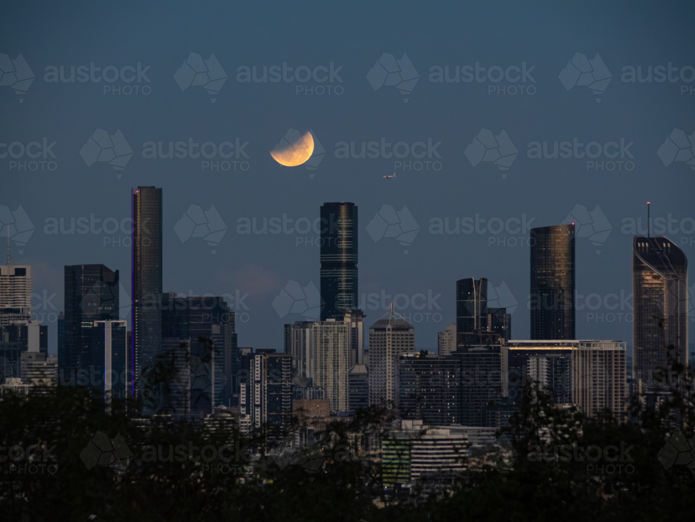 Eclipse of the full moon shining over city skyline - Australian Stock Image