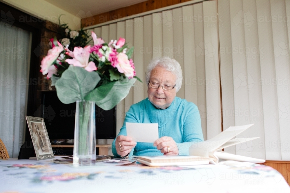Elderly lady browsing through photographs - Australian Stock Image
