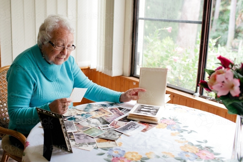 Elderly lady browsing through photographs - Australian Stock Image