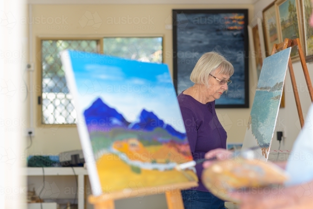 Elderly lady painting in art studio - Australian Stock Image