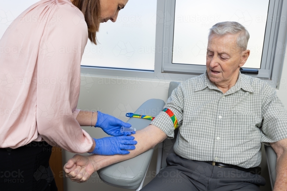 elderly male patient sitting in phlebotomy chair for blood test - Australian Stock Image