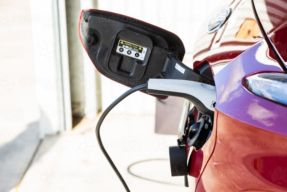 Electric vehicle car charging at home in shed - Australian Stock Image