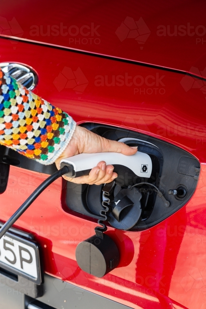 Electric vehicle charging plug being plugged in to car - Australian Stock Image