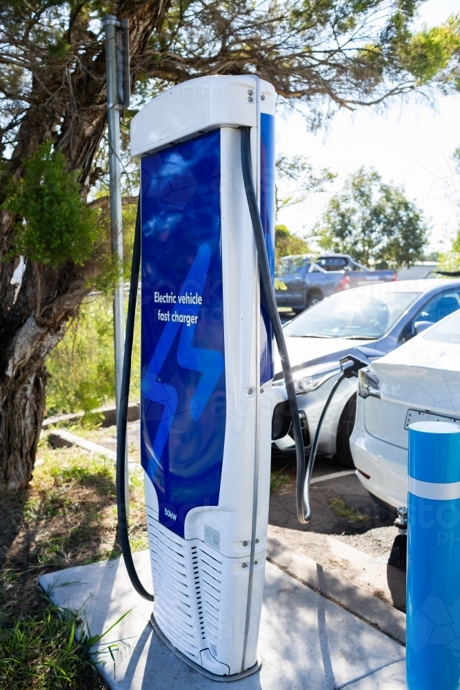 Electric vehicle fast charger with EV car plugged in to charge up on road trip - Australian Stock Image