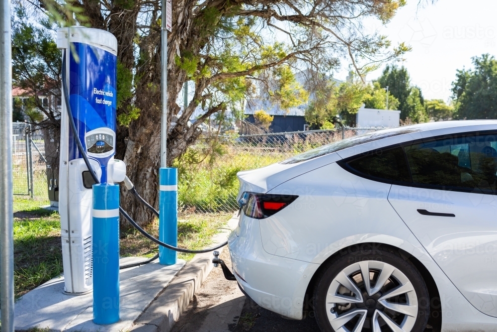 Electric vehicle fast charger with EV car plugged in to charge up on road trip - Australian Stock Image