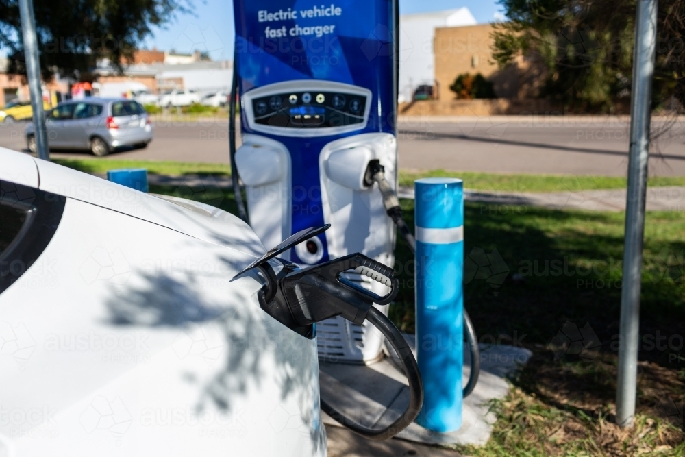 Electric vehicle fast charger with EV car plugged in to charge up on road trip - Australian Stock Image