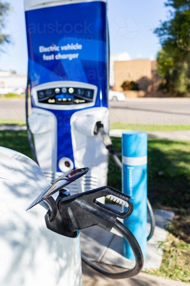 Electric vehicle fast charger with EV car plugged in to charge up on road trip - Australian Stock Image