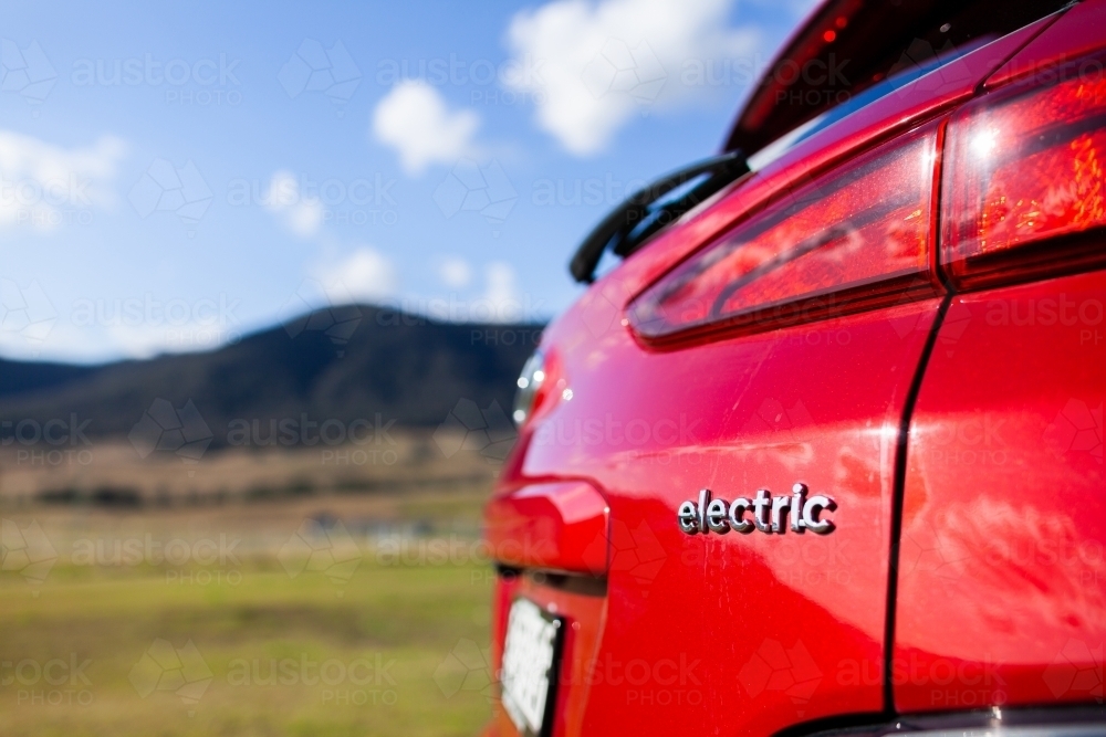 Electric word in back of red electric vehicle car in rural country setting - Australian Stock Image