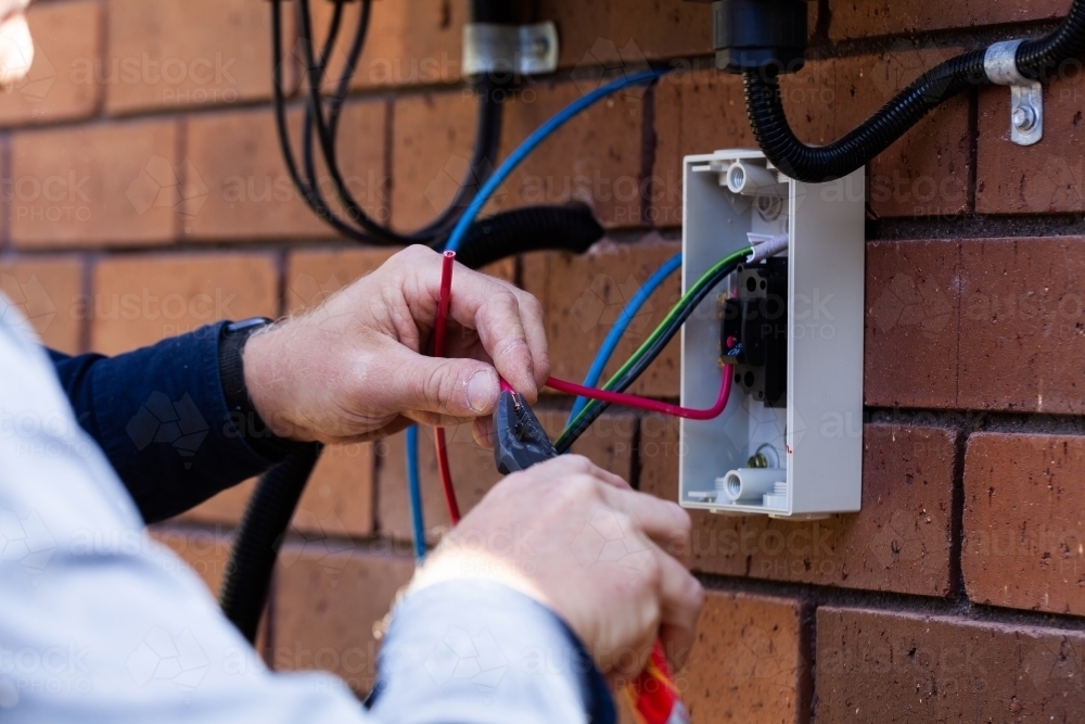 Electrician cutting wires while installing solar power on house - Australian Stock Image