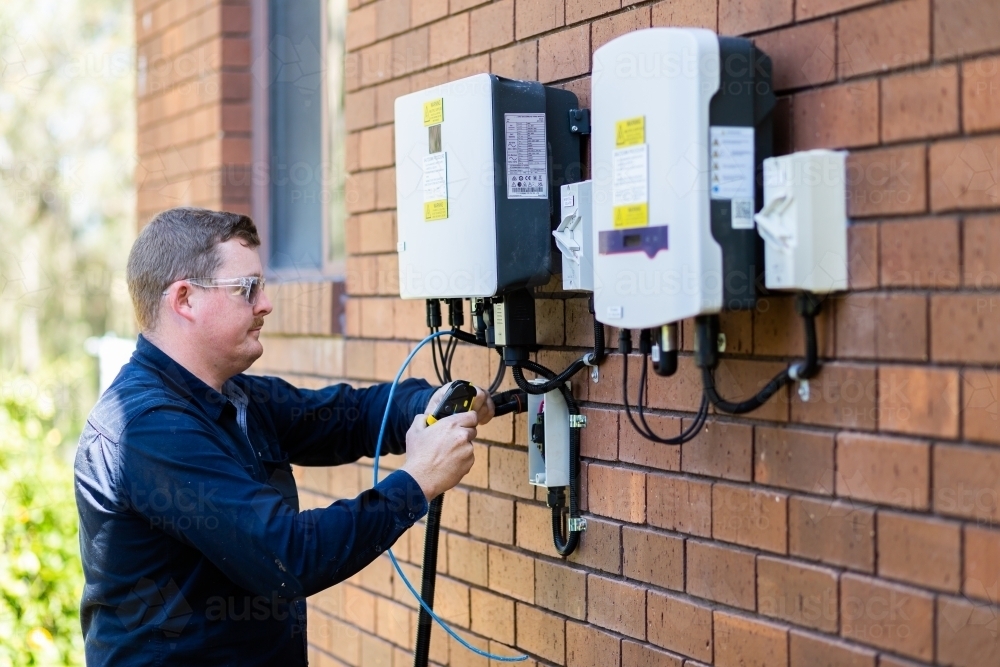 Electrician installing solar power connection to house - Australian Stock Image