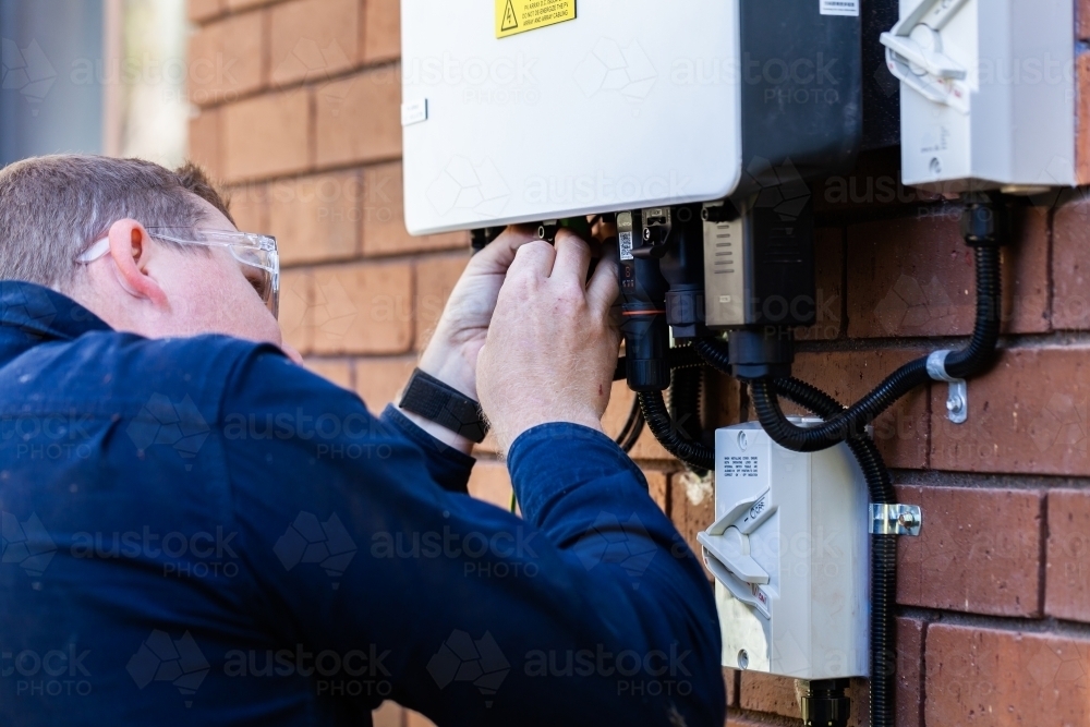 Electrician plugging in plugs to activate solar power - Australian Stock Image