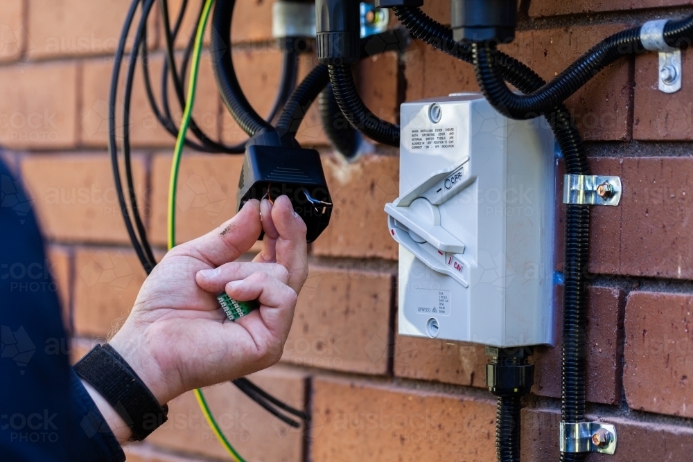 Electrician wiring up solar power system to house as part of the NSW Rebate Solar - Australian Stock Image