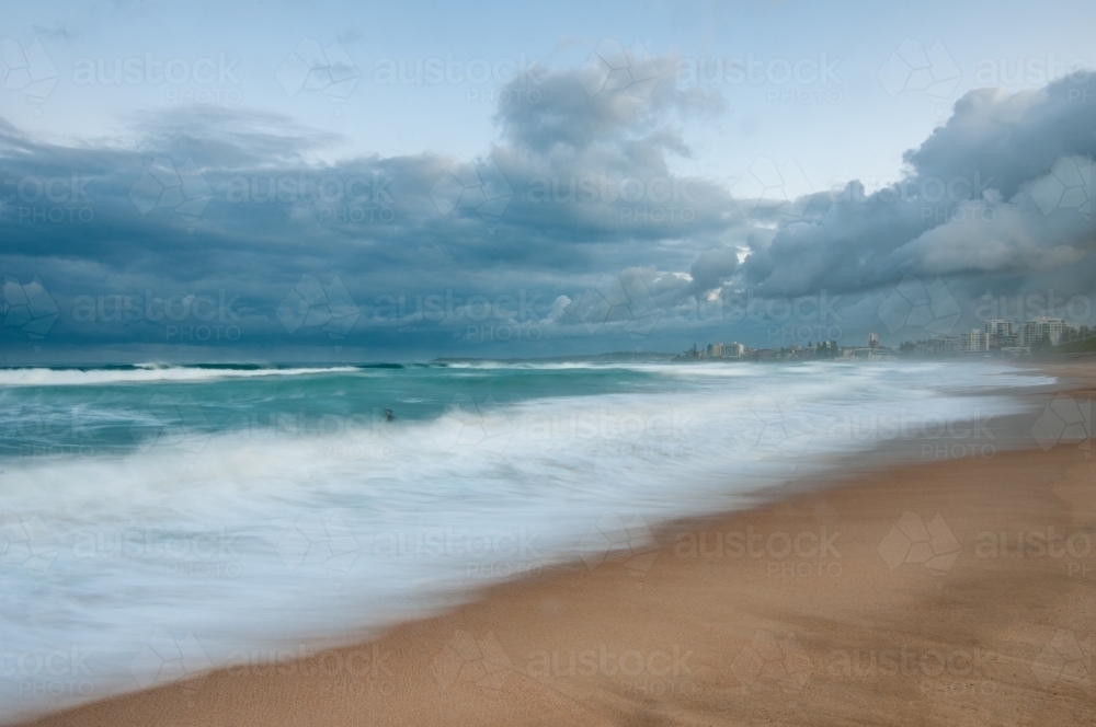 Elouera Beach surf long exposure with lone surfer - Australian Stock Image