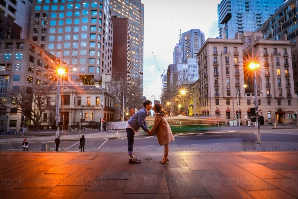 Engaged couple embracing in the city with Melbourne cityscape in background at night - Australian Stock Image