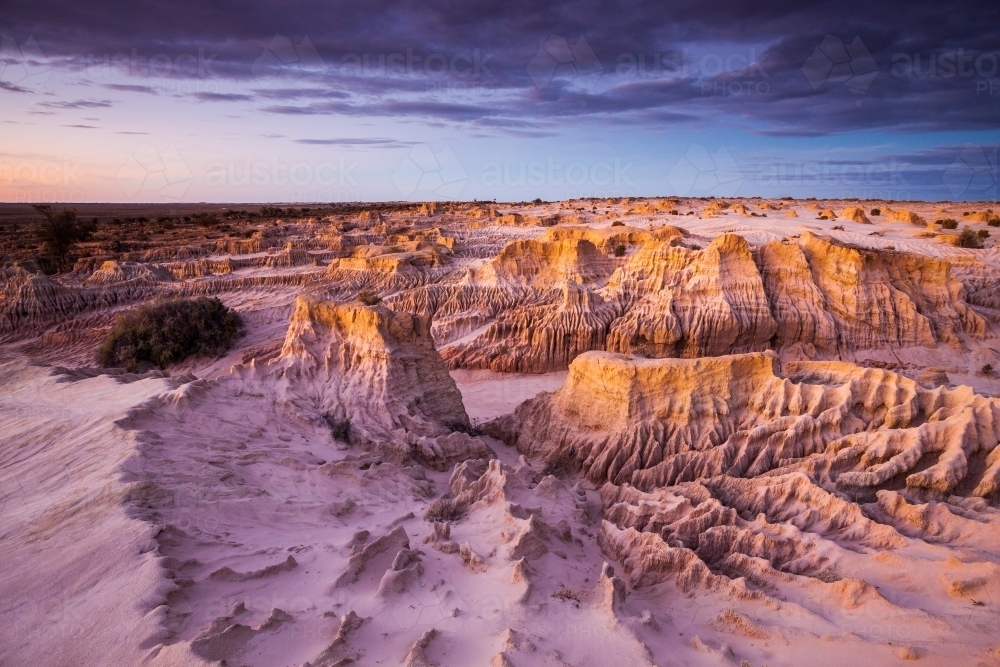 Eroded landscape of middens and creek beds at sunset - Australian Stock Image