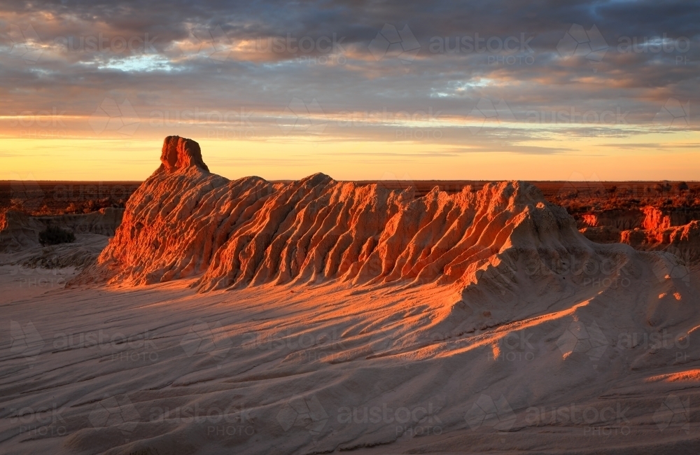 Eroded, sand and clay crusted desert landforms glow in rich colour - Australian Stock Image