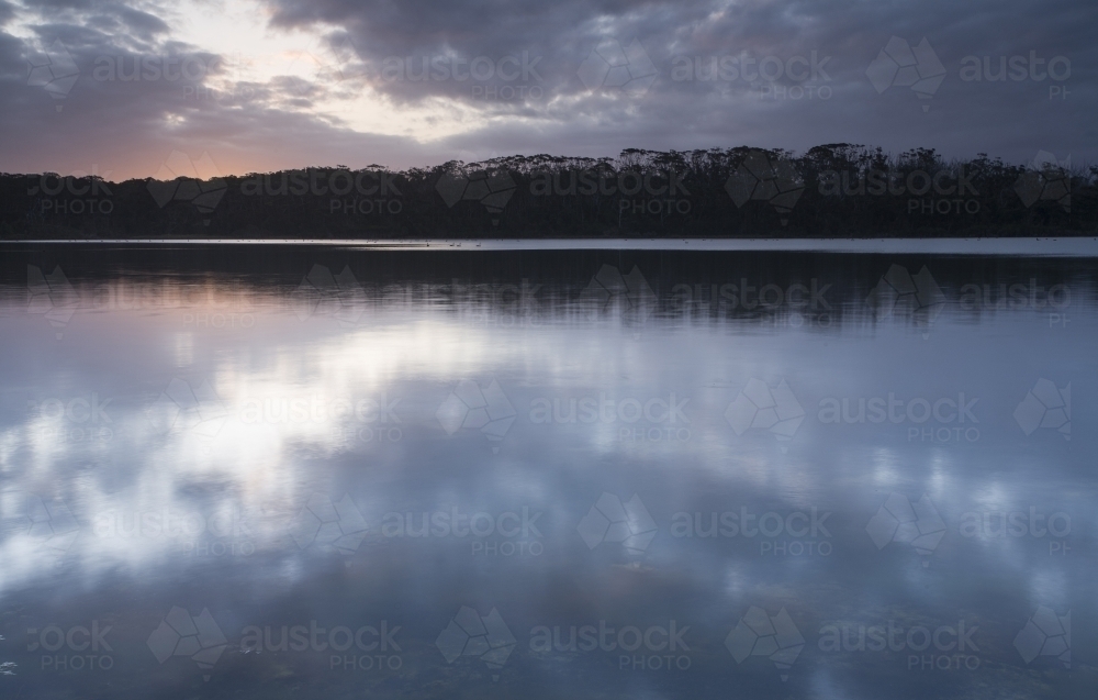 Evening sky and clouds reflected in serene lakes waters - Australian Stock Image