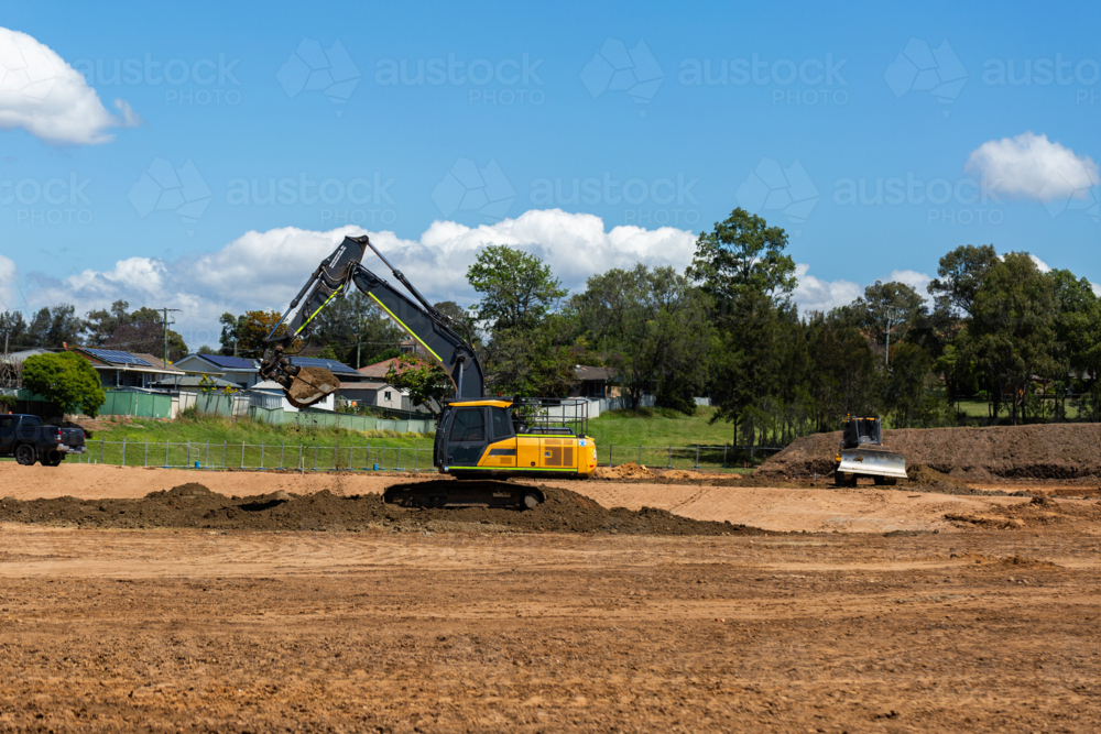 Excavator digging dirt on construction site with earthmoving machinery - Australian Stock Image