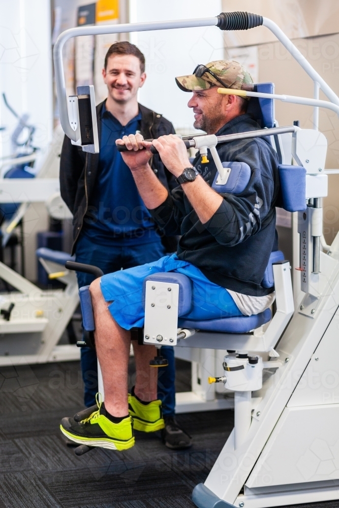 exercise therapy equipment at physiotherapy clinic with happy man using it at treatment - Australian Stock Image