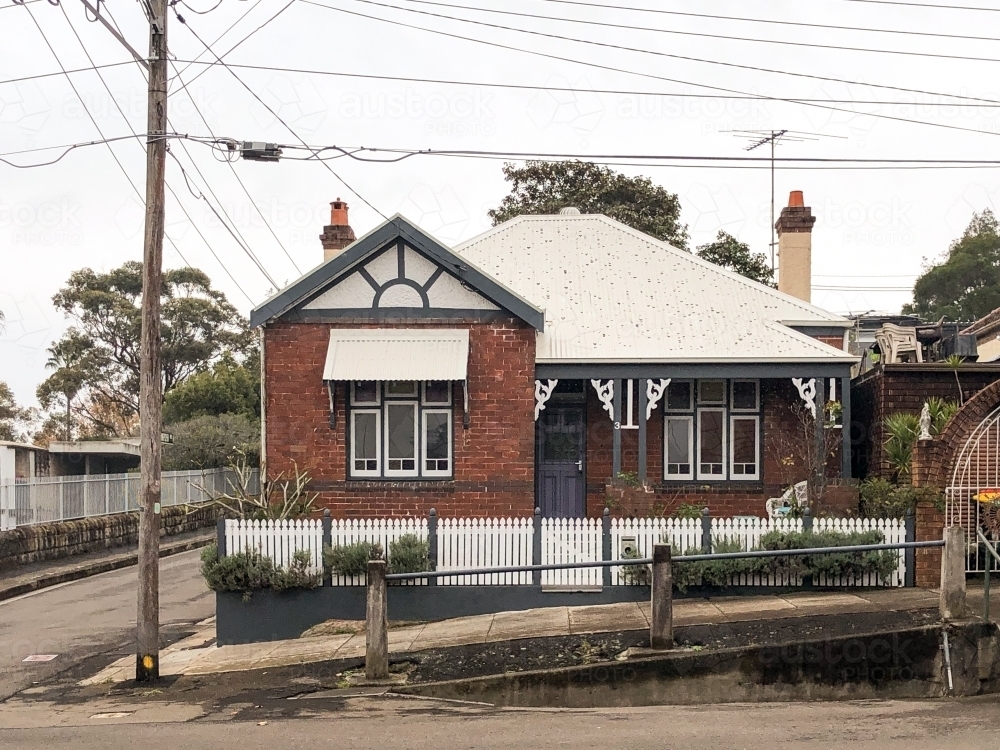 facade of a house made with bricks and white roof with black fence - Australian Stock Image