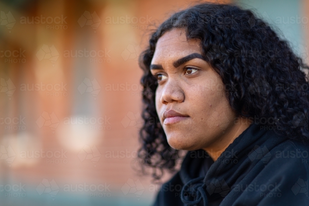 face of a noongar girl with blurry building in background - Australian Stock Image