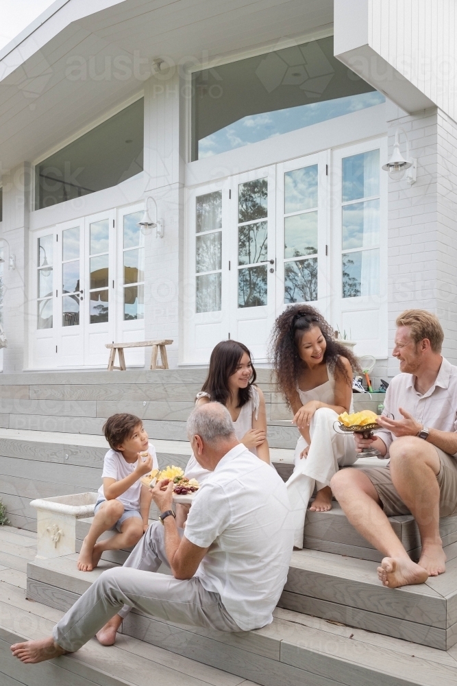 Family eating snacks on backyard stairs - Australian Stock Image