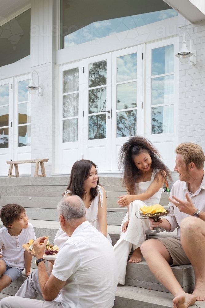 Family eating snacks on backyard stairs - Australian Stock Image