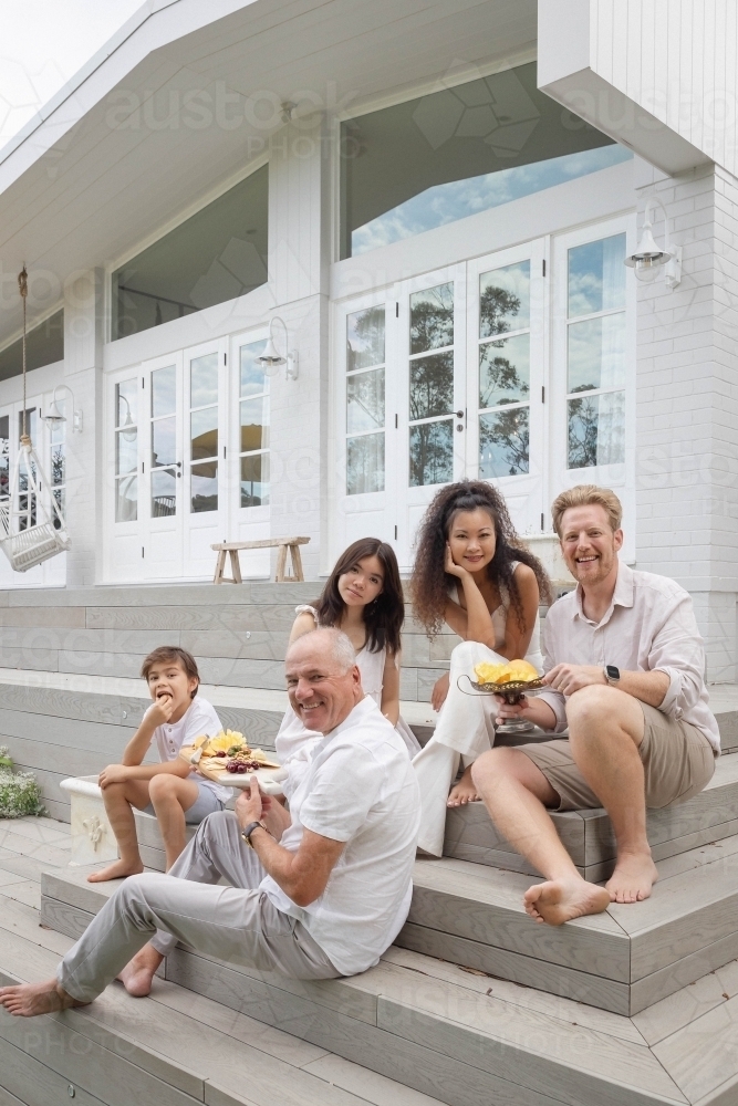 Family eating snacks on backyard stairs - Australian Stock Image