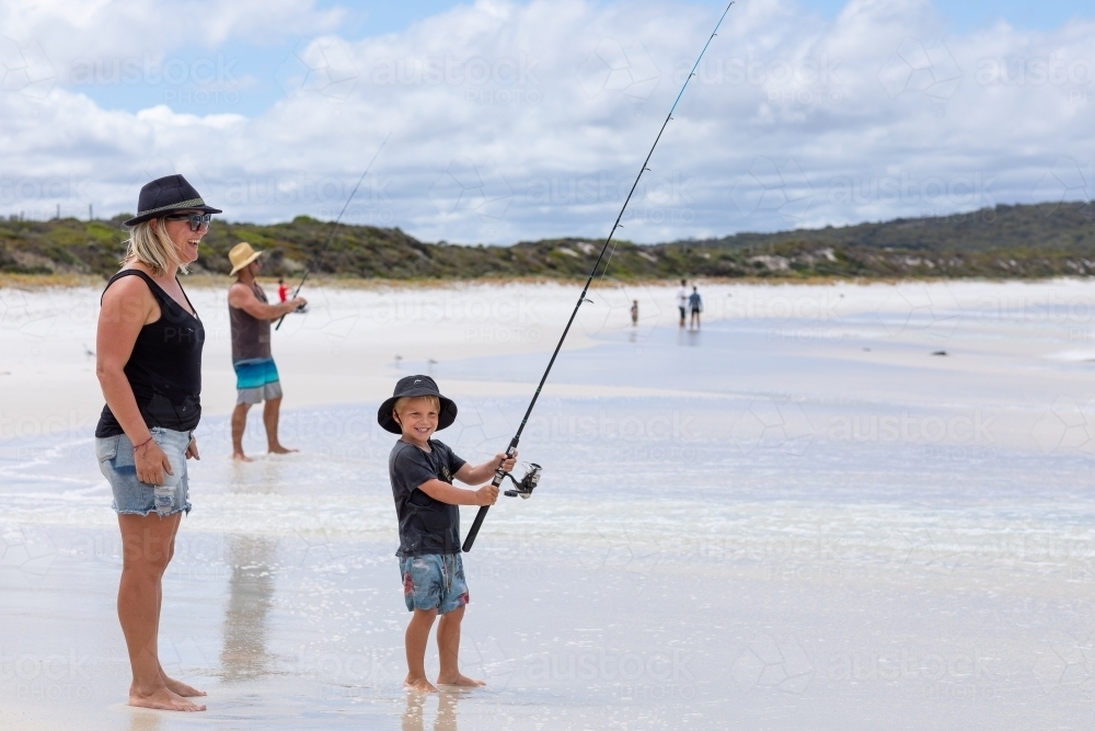 family fishing on white sand beach - Australian Stock Image