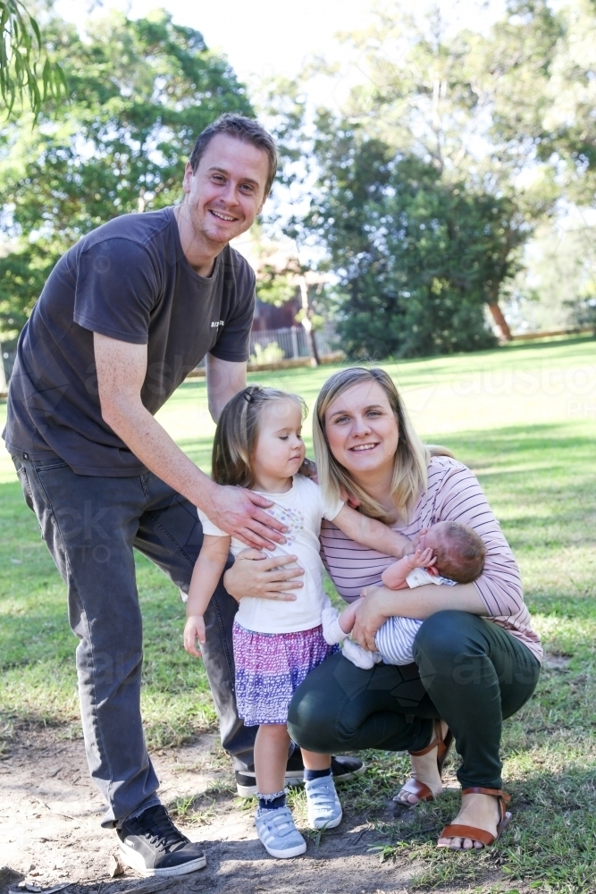 Family group with a new-born baby in a green, shady park - Australian Stock Image