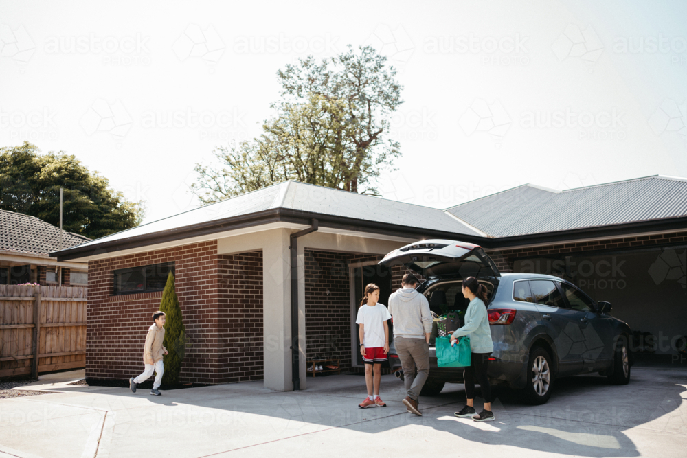 Family loading things into the boot of the car. - Australian Stock Image