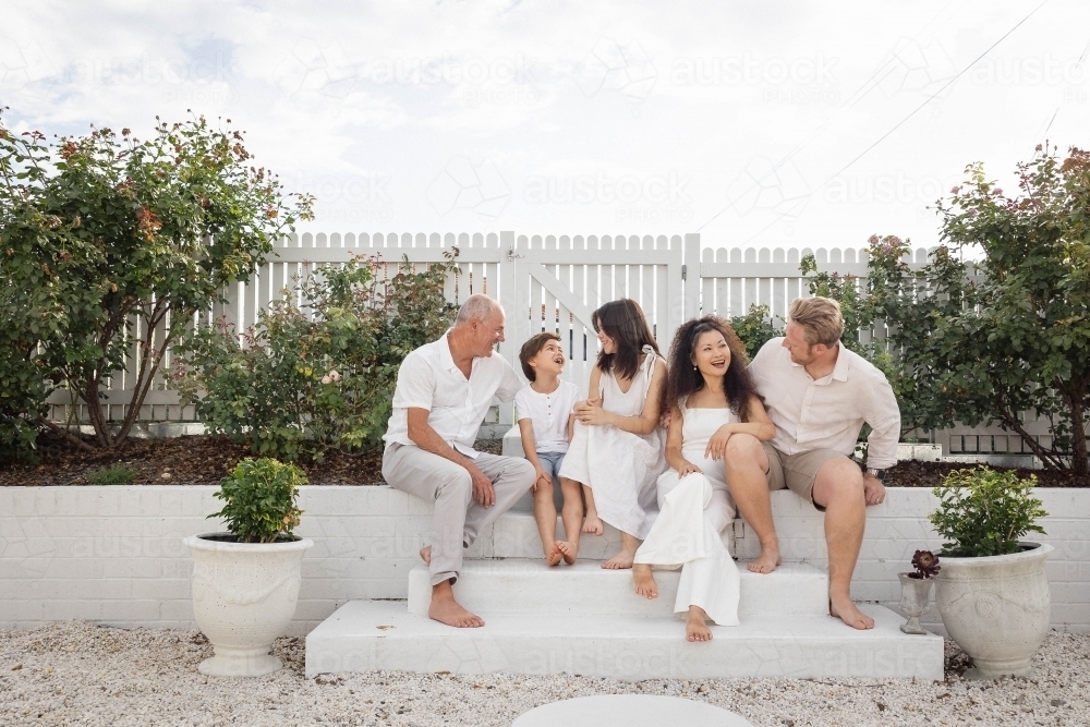 Family of five sitting on backyard steps - Australian Stock Image