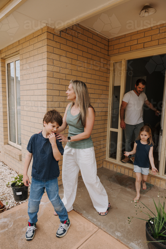 Family of four coming out of the house. - Australian Stock Image