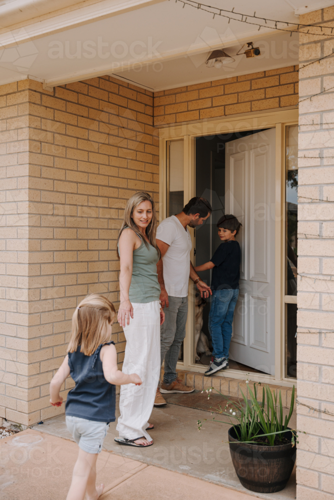 Family of four going into their house through front door - Australian Stock Image