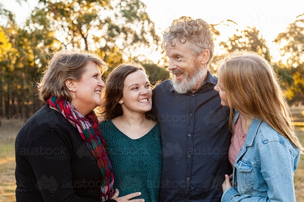 Family of four with adult children looking at one another laughing - Australian Stock Image