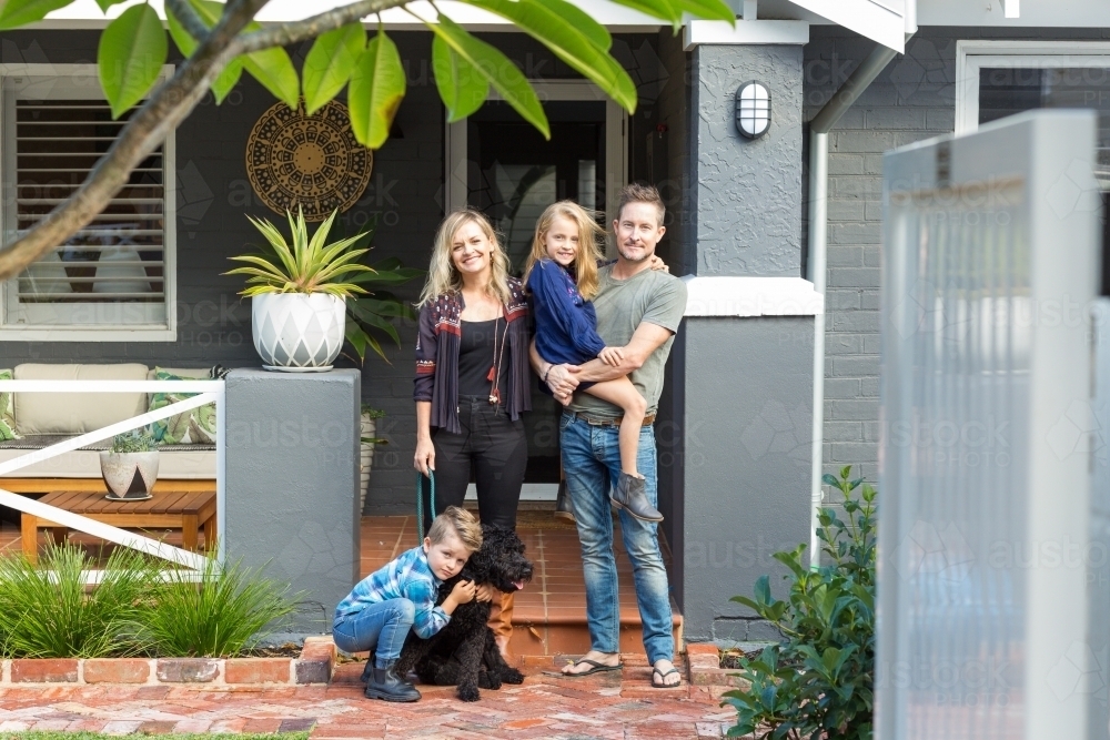 Family of four with pet dog in front of suburban home - Australian Stock Image