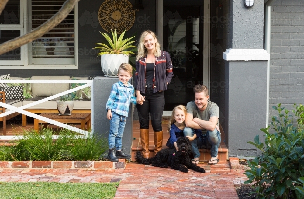 Family of four with pet dog in front of suburban home - Australian Stock Image