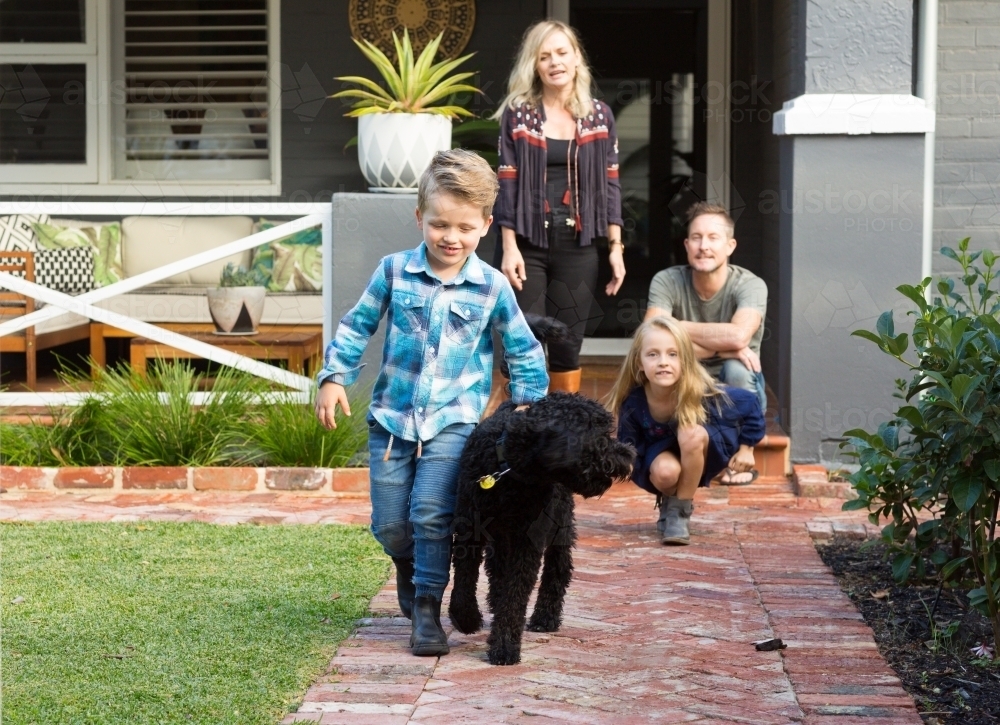 Family of four with pet dog in front of suburban home - Australian Stock Image