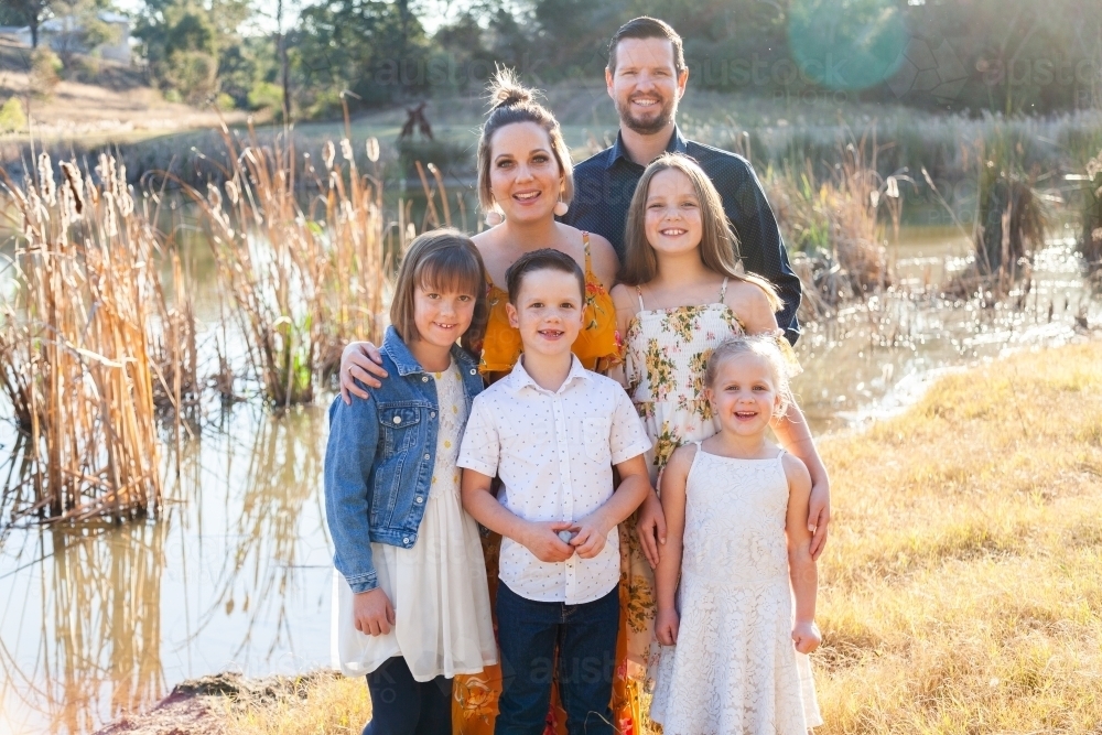 Family portrait beside dam in sunlight - Australian Stock Image