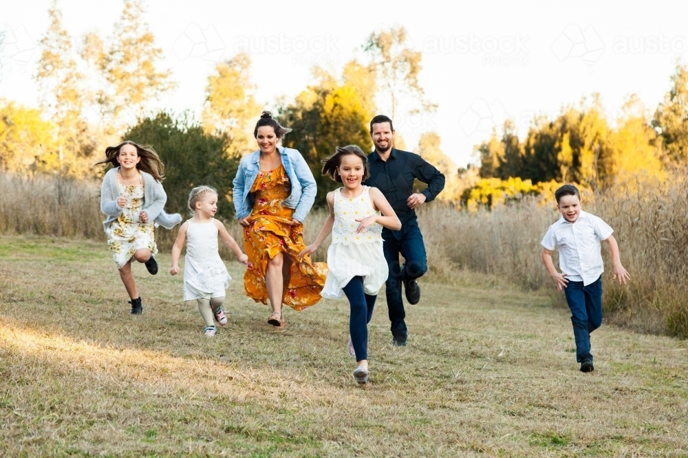 Family running together through park - Australian Stock Image