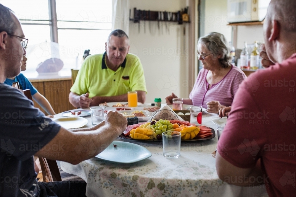 Family sitting around table eating and drinking - Australian Stock Image