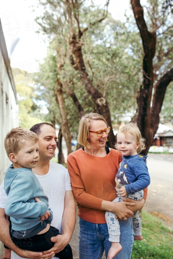 Family walking down footpath with parents carrying children - Australian Stock Image