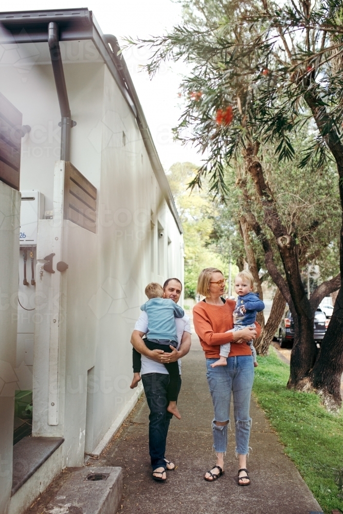 Family walking down footpath with parents carrying children - Australian Stock Image